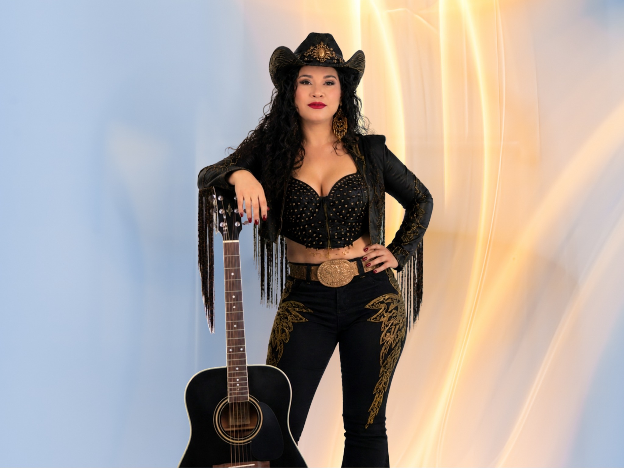 Natasha Melo com figurino preto e dourado ao lado de um violão